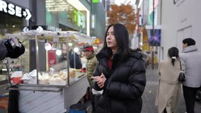 Slow-motion video of a Korean man in his 30s strolling around the night market on a cold winter night in Myeong-dong, Seoul, South Korea