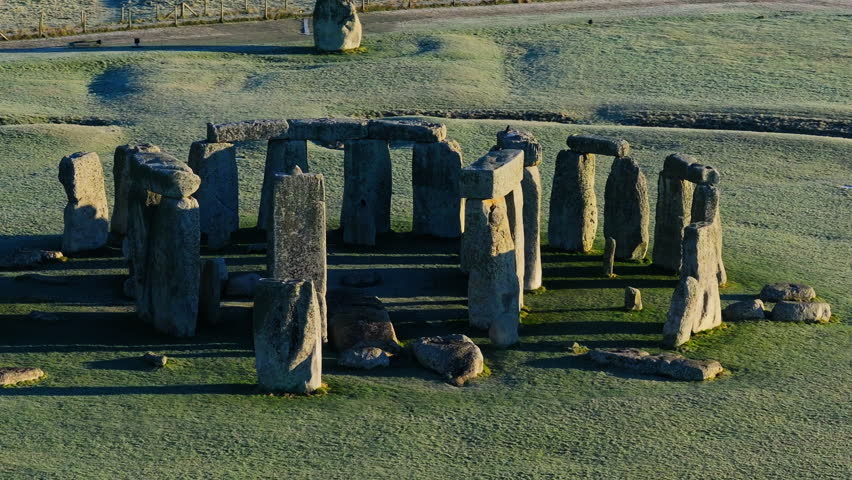 Aerial shot circling around Stonehenge in bright low sunlight casting long shadows Royalty-Free Stock Footage #3418814121