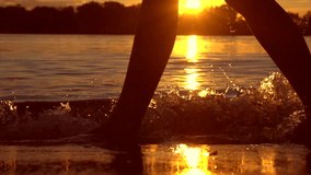 Woman walking on beach barefoot over sunset. Girl walking in shallow water at sunset and enjoying nature. Seashore, ocean. Healthy lifestyle concept. Slow motion 240 fps. 4K UHD video