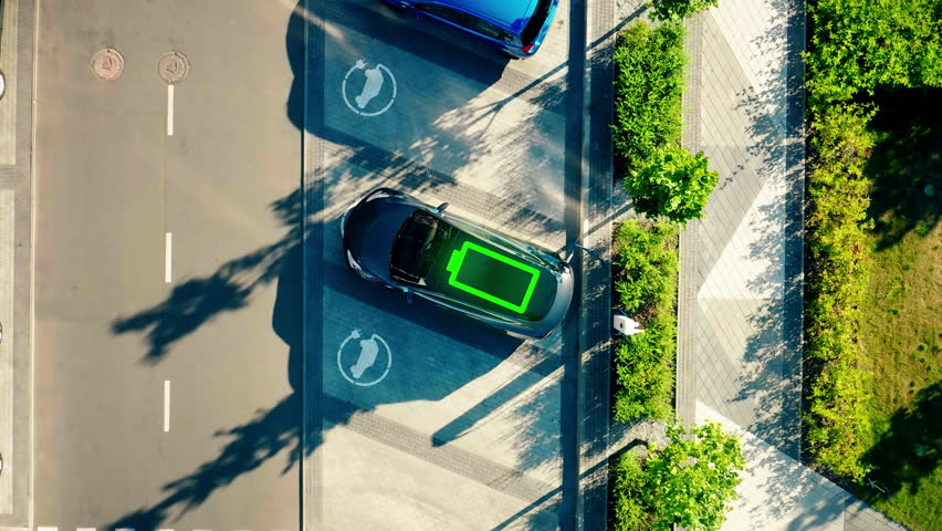 Charge station for electric cars. Electric car charger. Zero emission vehicle on EV only charging station. Aerial view 4K. Battery icon indication of charging.  Royalty-Free Stock Footage #3418864227