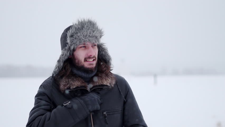 bearded man in earflaps and snow