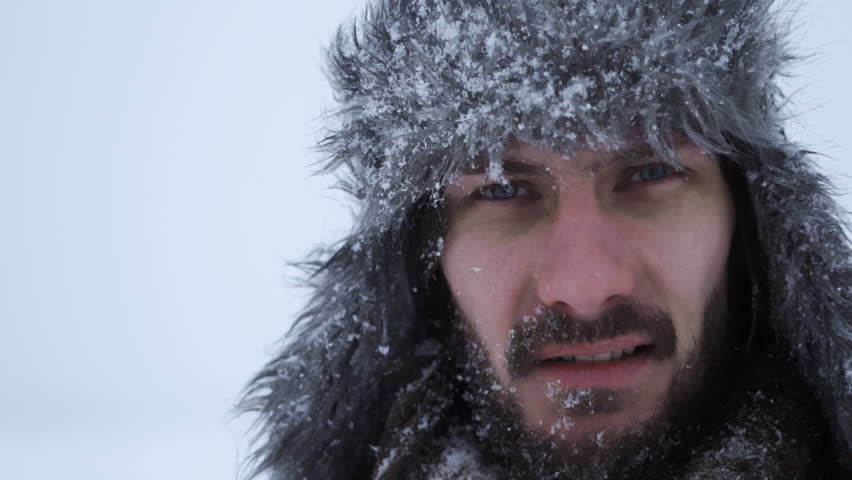bearded man in earflaps and snow
