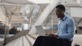Young Handsome Businessman Using Laptop for Online Meetings, Waving to Clients. African American Student Studying Online While Sitting Outside. People and Technology Concept - Powered by Shutterstock - Get 15% off with code: PIKWIZARD15