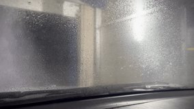 View of an automatic car windshield wash with foam Automatic car wash view from the car cabin. Sliding foam from the windshield. View from inside. Time to wash the car. - Powered by Shutterstock - Get 15% off with code: PIKWIZARD15