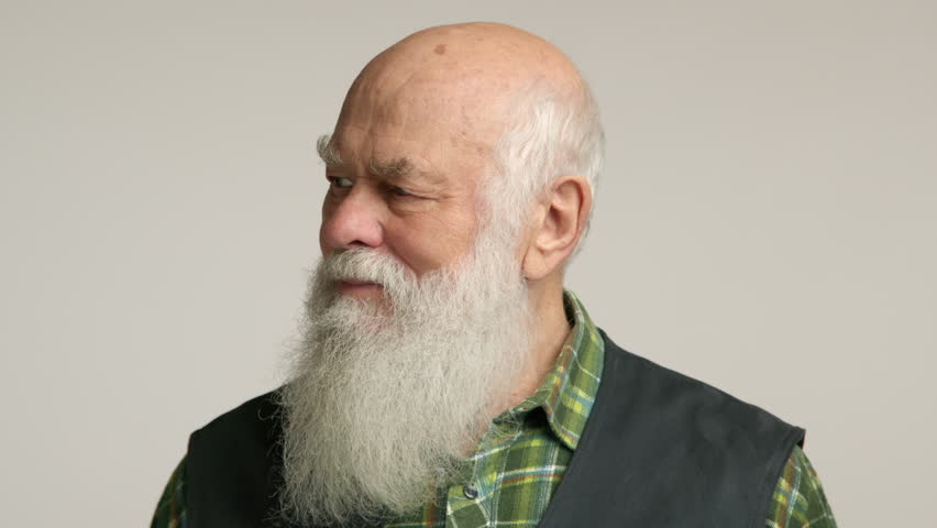 Studio portrait of a senior man with a kind, inviting smile, dressed casually in a vest over a plaid shirt, suggesting friendliness and a relaxed demeanor. Camera 8K RAW. 
