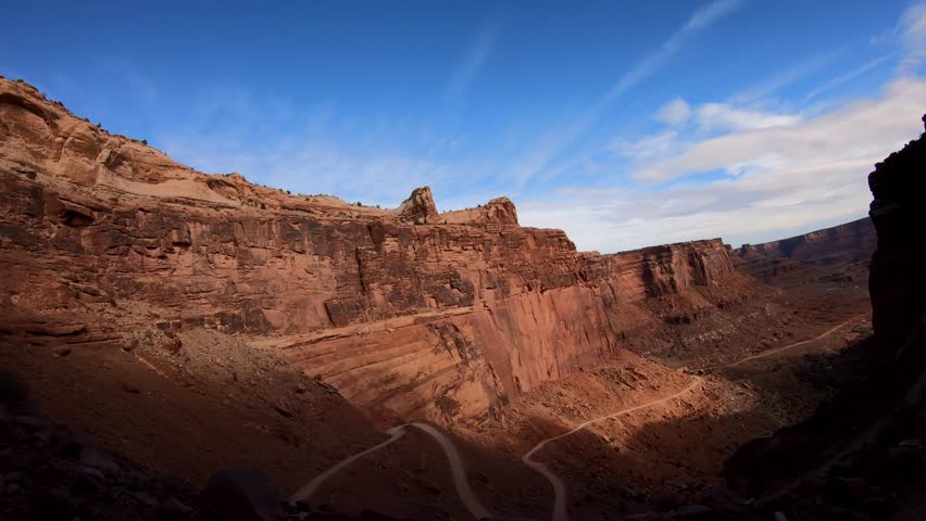 A side view perspective of the descent of Shafer Switchbacks; the red rock ledges and cliffs encroaching, with each hairpin turn revealing new stomach-dropping slopes angling dangerously below. 