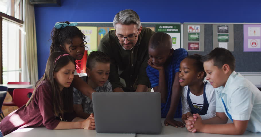 Diverse male teacher and group of schoolchildren looking at laptop. children at primary school in summer. Royalty-Free Stock Footage #3419325511