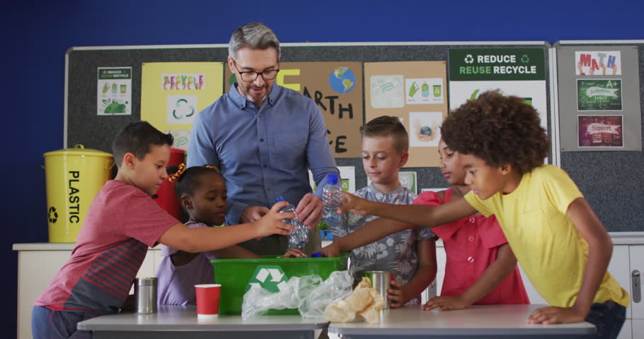 Diverse teacher and schoolchildren standing in classroom learning about recycling trash. children in primary school.