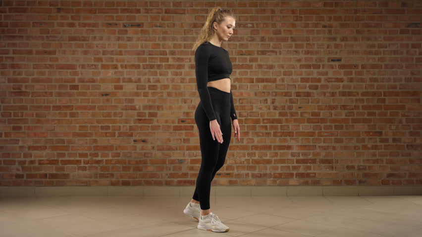 One leg Romanian deadlift. A trainer skillfully demonstrates how to perform the exercise, one leg Romanian deadlift. A girl in good physical shape. She is in black sportswear in a loft gym. 8K RAW. Royalty-Free Stock Footage #3419355755