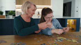 Joyful down syndrome woman and her mother assembling puzzles at home