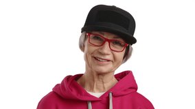 Capturing the essence of vivacity, a woman over 65 exudes happiness in her trendy red hoodie, complemented by a sleek black cap and matching red glasses, set against a pure white background. 8K RAW. 