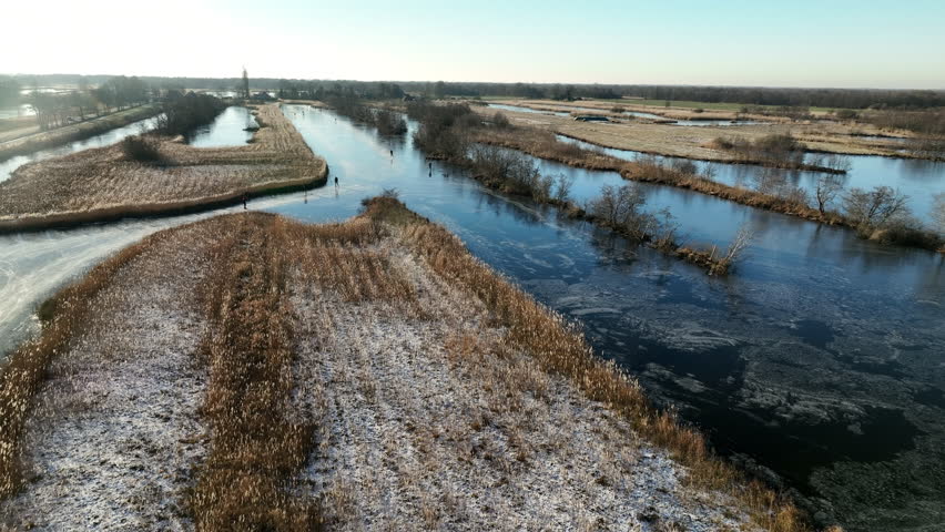 Ice skating on a frozen lake in the Weerribben Wieden nature reserve seen from above during a cold winter day in The Netherlands.
