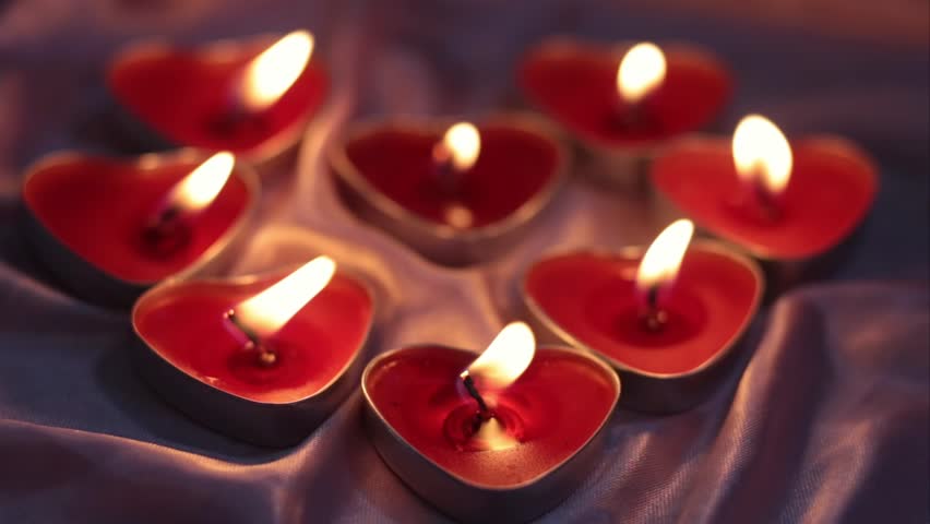Red burning candles in the shape of a heart with a blazing flame. Tongues of fire on a red background. Valentine