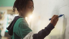 Talented Small Boy Solving an Arithmetic Equation. Portrait of a Happy Elementary African American Pupil Studying Hard, Writing Numbers on a Whiteboard During a Math Class - Powered by Shutterstock - Get 15% off with code: PIKWIZARD15