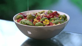 Pouring olive oil and balsamic vinegar on fresh salad with lettuce leaves, sun-dried tomatoes, mozzarella cheese, capers and olives. Healthy food concept. Dressing summer salad with oil - Powered by Shutterstock - Get 15% off with code: PIKWIZARD15