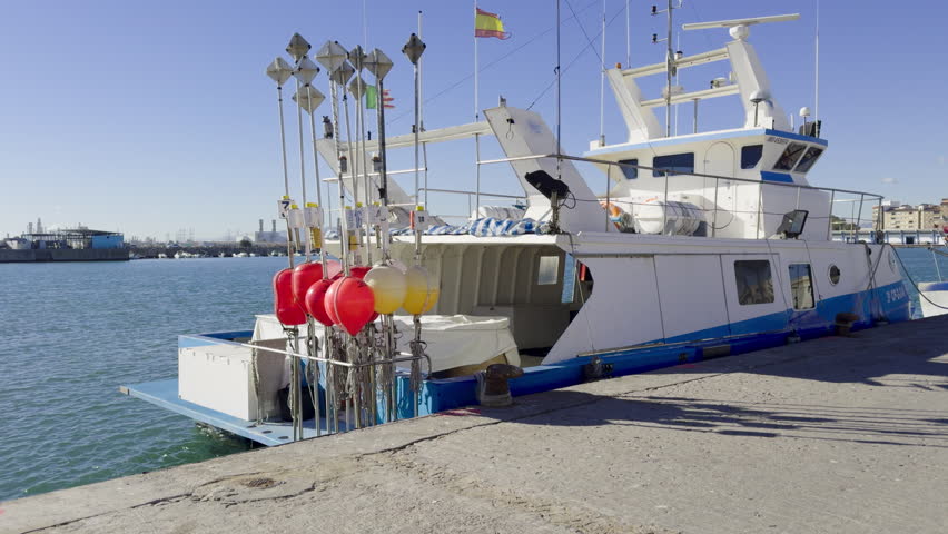 Fishing boats and ships in the port of Castellon in winter. Port cranes on the horizon. Red floats for nets. Port of El Grao. Spain