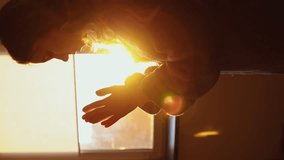 girl folds her hands palm to palm and prays in the room by the window at sunset. vertical video