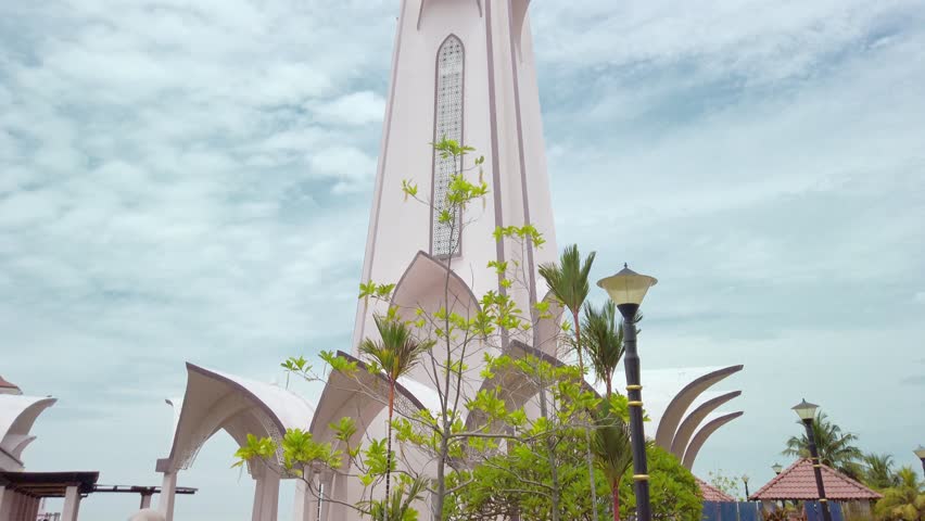 Cinematic low-to-high shot of the minaret of Masjid Selat Melaka in Melaka, Malaysia, during a cloudy day in daylight. Royalty-Free Stock Footage #3419659787