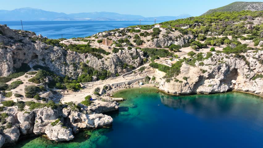 Aerial drone video of iconic archaeological site of Heraion built by the sea forming a small secluded beach,near lake Vouliagmeni, Loutraki, Perachora, Greece