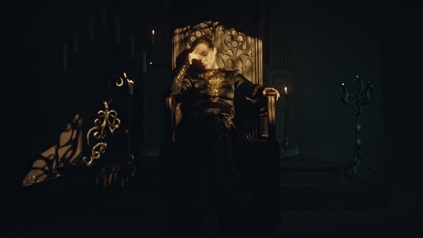 A young woman in a black long dress sits in a wooden carved throne in a dark Gothic church. Meditation and expression. Fashion and Cinematic concept