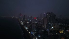 Aerial night view of Colombo cityscape shows lights, ocean, urban architecture. High-rise buildings, busy streets, skyline shot film, ad, real estate, urban planning. Coastal city, illuminated.