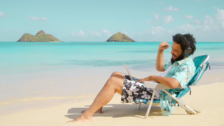 African American Young guy with the headphones and the laptop sitting on a beach chair at the island and working remotely, happy excited talking on the zoom. Remote work, outside office in Paradise Royalty-Free Stock Footage #3419824911