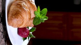 closeup of croissant sprinkled with powdered sugar with strawberries mint leaves delicious dessert french breakfast restaurant serving cook at home decorate many different videos