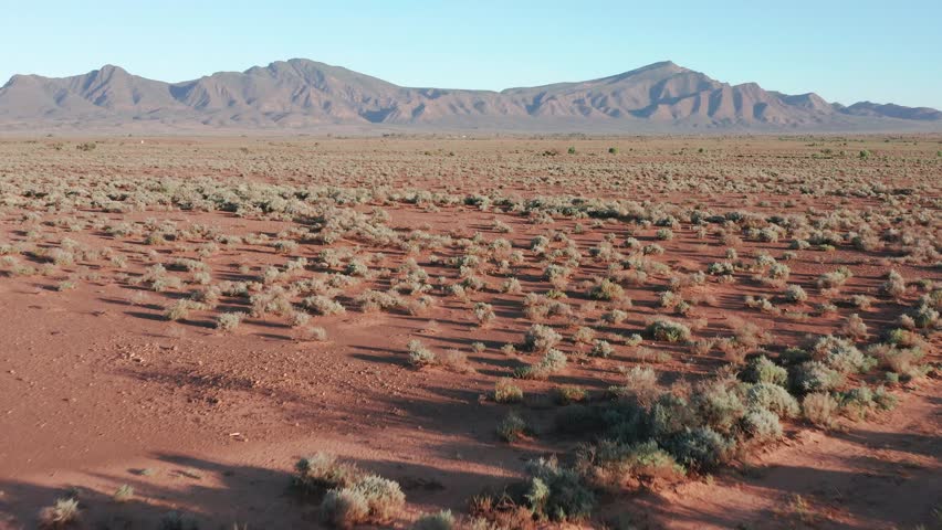 Fast drone shot above desert with Flinders Ranges mountains in background, South Australia