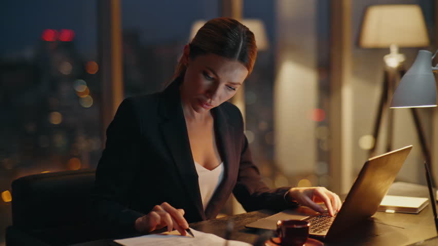 Tired lady overworking office typing laptop computer at night. Busy stressed manager feeling fatigue working with project deadline. Exhausted employee checking papers analyzing report in dark evening.