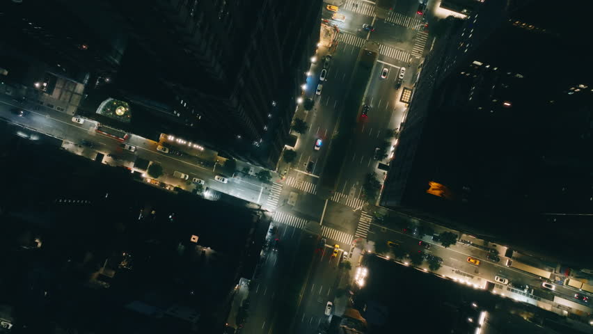 Aerial overhead descending view of Police vehicle with blue and red lights siren on stopped driver for speeding. Road accident on Manhattan at night. Top down cars driving by crossroad New York City Royalty-Free Stock Footage #3419866919