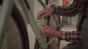 Young man installs bicycle accessory at home in studio apartment. Man sets up a bike at home. Male fixing bike at home gravel bike. Concept of fixing and preparing the bicycle for the new season