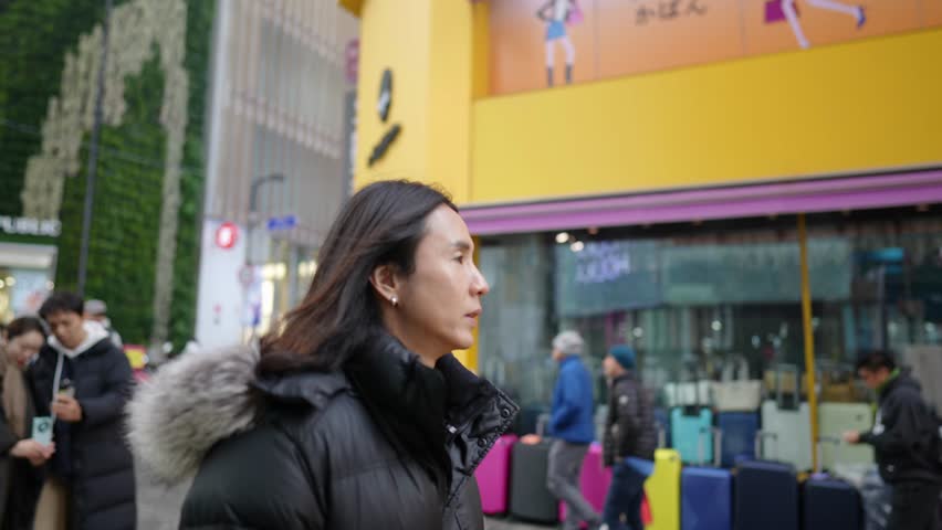 Slow-motion video of a Korean man in his 30s walking on the main street of Myeong-dong, Seoul, South Korea in the cold winter