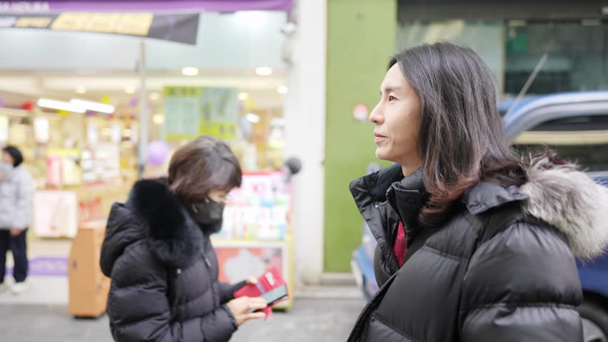 Slow-motion video of a Korean man in his 30s walking on the main street of Myeong-dong, Seoul, South Korea in the cold winter