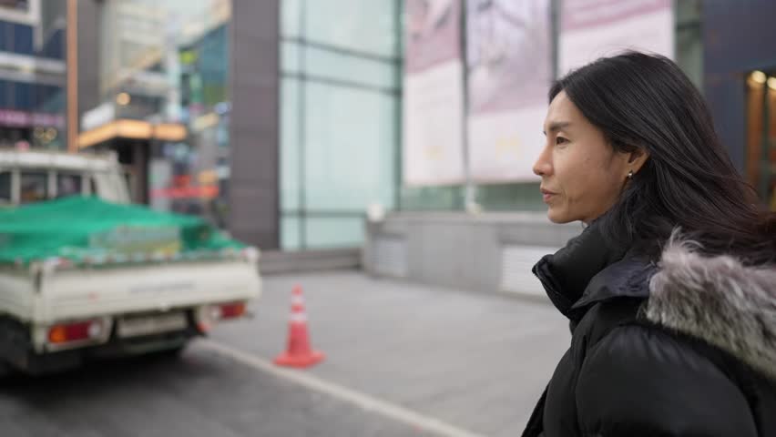 Slow-motion video of a Korean man in his 30s walking on the main street of Myeong-dong, Seoul, South Korea in the cold winter