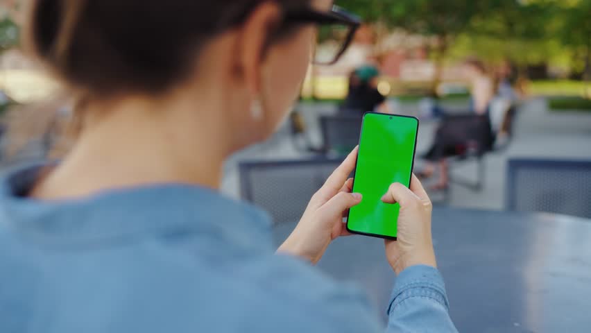 Woman is standing on the street and using smartphone with green screen