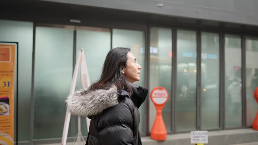 Slow-motion video of a Korean man in his 30s walking on the main street of Myeong-dong, Seoul, South Korea in the cold winter