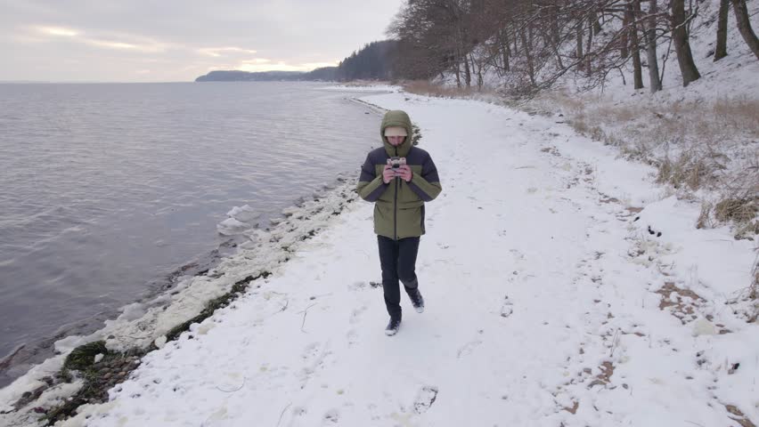 Man Walks on Snowy Beach During Winter Season and Film Himself With A Drone