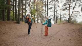 Senior hikers hike on nature autumn park holding nordic sticks enjoying nature route. Tourists man woman trekking carrying backpacks with touristic equipment. Nordic walking travel tourism. - Powered by Shutterstock - Get 15% off with code: PIKWIZARD15