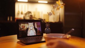 Person eating food while watching VTuber streamer on laptop monitor 4K