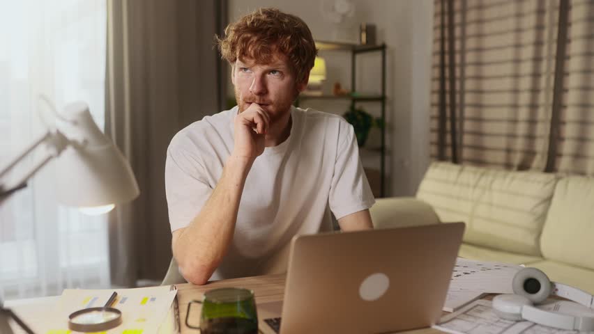 Sad red haired man student or freelancer with lack of new ideas or creative block typing and deleting text on laptop computer at home Worried male changing his mind every few seconds indoors Royalty-Free Stock Footage #3420236915