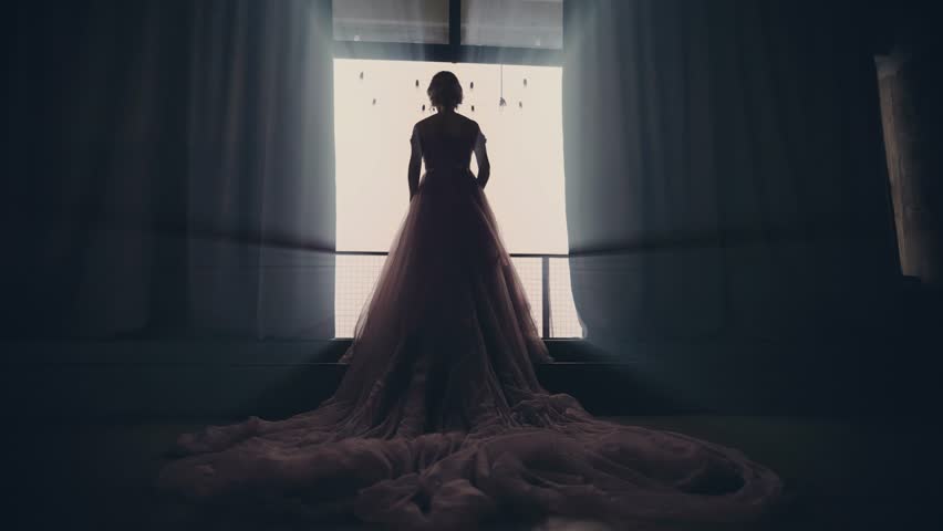 mysterious woman in purple luxurious dress long train walks in dark room towards window balcony. Fantasy girl princess back rear view evening gown go to magic light. Royal queen sexy bride wedding. 4k