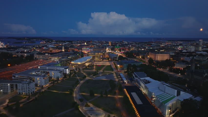 Aerial panoramic view of night city. Illuminated modern town development around public park. Helsinki, Finland