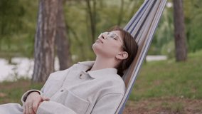 Video of young woman relaxing in hammock in park after busy day