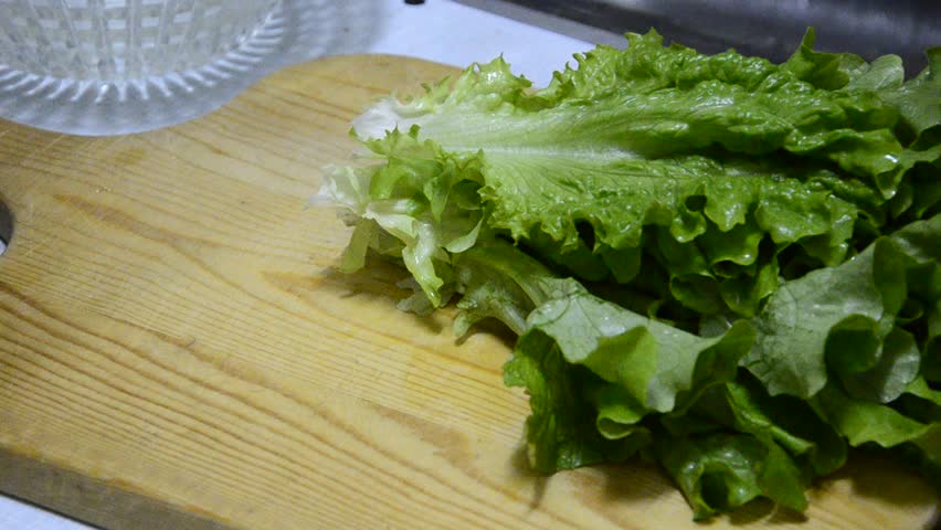 chef chopping lettuce green salad on wooden board