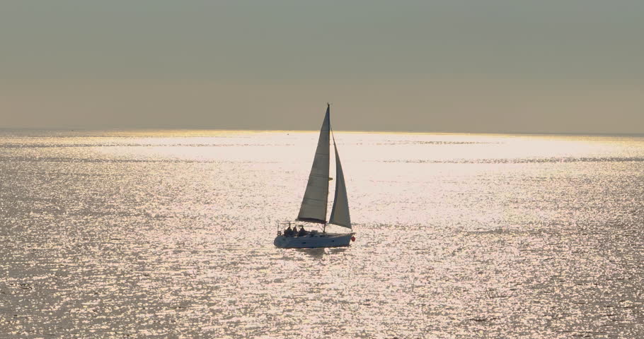 Drone tracking shot of luxury sailing yacht cruising in open blue ocean. Drone shot view of yachts sailing towards US. Sea transportation. Yachting with sails up at windy day