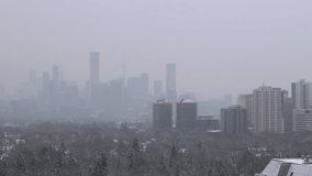 Toronto skyline in winter with falling snow. Downtown landmark buildings are barely visible in the time lapse video