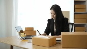 Starting a small business. Asian woman SME owner checks online orders. Selling products that work with boxes, freelancing at home, online sme business, small medium enterprises, 4k video