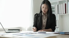 Young Asian business woman doing statistics planning and holding a chart, graph tablet and staff taking notes. Financial statistics success concept, 4k video