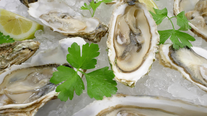 Dish with oysters. Fresh raw molluscs with lemon on crushed ice. View from above Royalty-Free Stock Footage #3420417139
