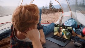 Two men talking video conference with laptop closeup. Traveling guy chatting by web camera resting tent on mountain trip. Cheerful happy friends sharing news on vacation. Happy brothers calling online
